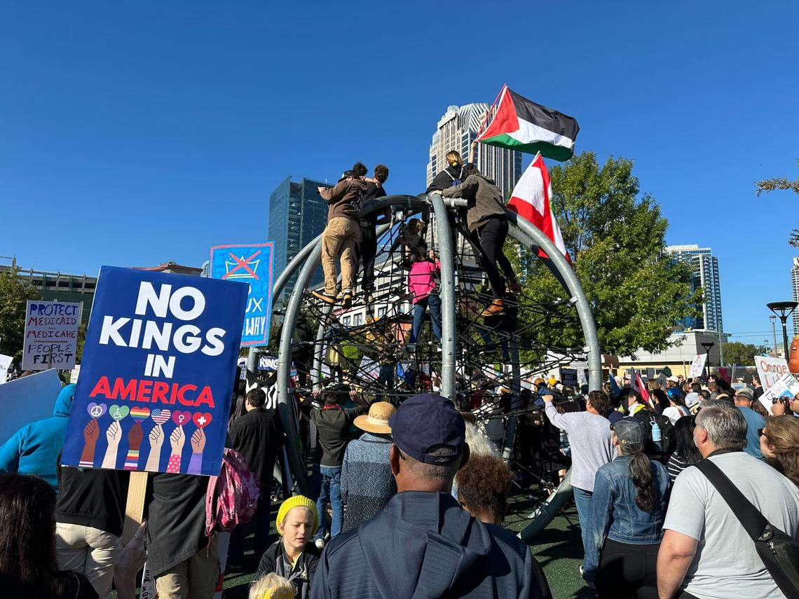 Protesters at the ‘No Kings’ rally in uptown Charlotte on Saturday, Oct. 18, raise Palestinian and Lebanese flags in First Ward Park as speakers begin to kick off the rally.