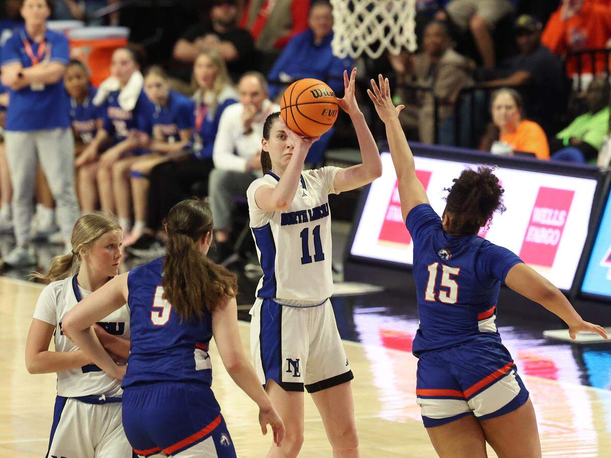 North Lincoln’s Lydia Cipriano, center, releases a jumper over the outstretched arm of SE Alamance defender Inysia McIver, right, during the 5A girls’ championship game on Saturday at Lawrence Joel Veterans Memorial Coliseum in Winston-Salem. North Lincoln defeated SE Alamance 59-56.