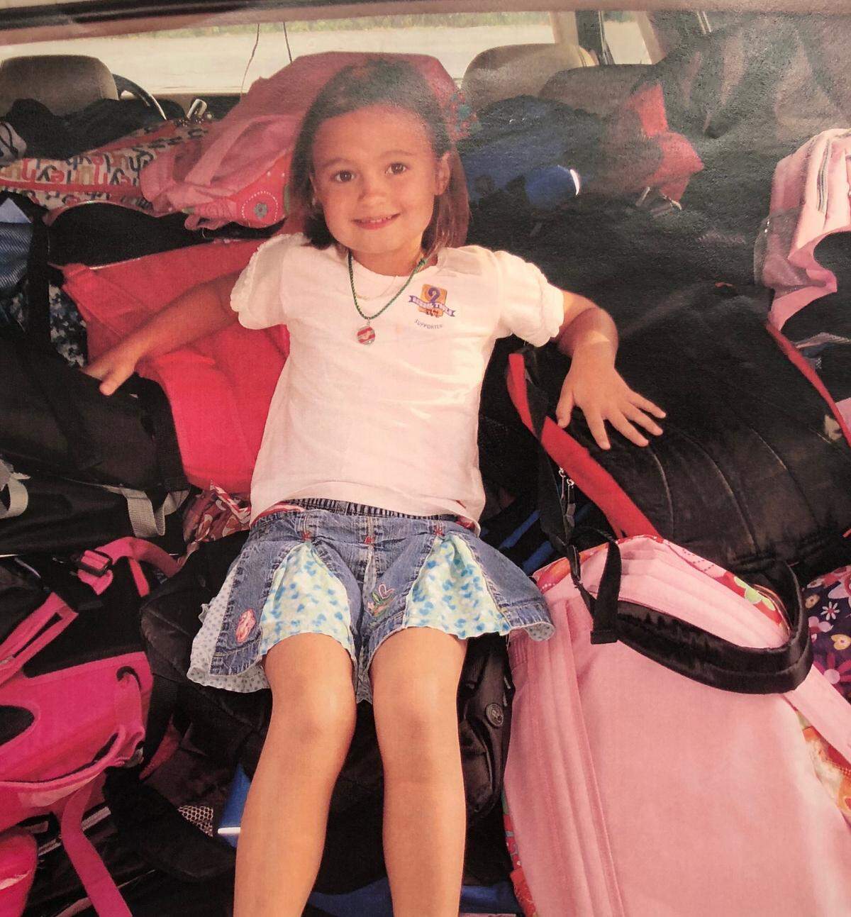 A Harrell family photo shows Little Jane reclining on top of a heap of backpacks collected for a drive she started leading when she was just 6.