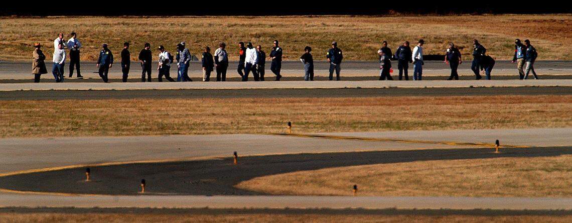 Photo from The Charlotte Observer on Jan. 9, 2003. Investigators search the runway at Charlotte Douglas International Airport for clues in the cause of the crash of flight 5481 that crashed, killing all 21 on board.