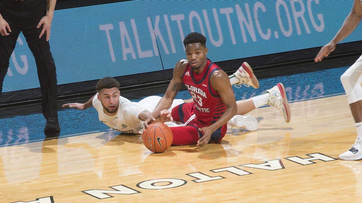 Charlotte’s Drew Edwards (left) and FAU’s Richardson Maitre (23) scramble for a loose ball.