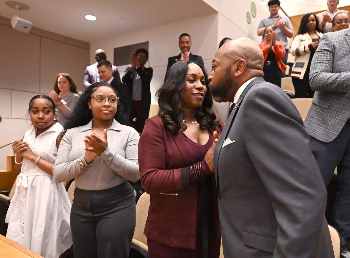 Michael Bryant, right, kisses his wife, LaShonda Bryant, center after giving remarks following an announcement that he will be the new Mecklenburg County Manager on Tuesday, April 1, 2025. At left are Bryant’s daughters Malia Bryant, and Myla Bryant.