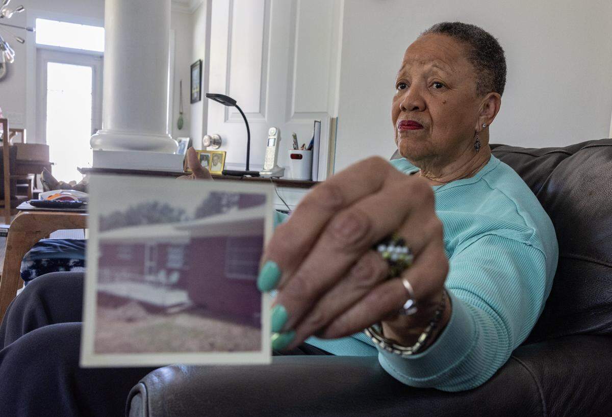 Darnell Ivory holds up a photo of the house her family lived in in Charlotte, N.C., on Friday, April 10, 2026. 