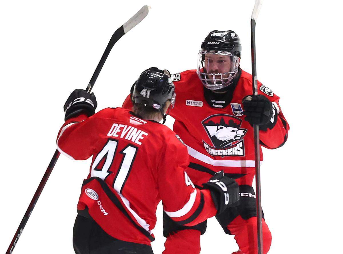 Charlotte Checkers forward Jack Devine, left, is congratulated by teammate Oliver Okuliar, right, following a goal against the Abbotsford Canucks in Monday’s Game 6 of the Calder Cup finals at Bojangles Coliseum.