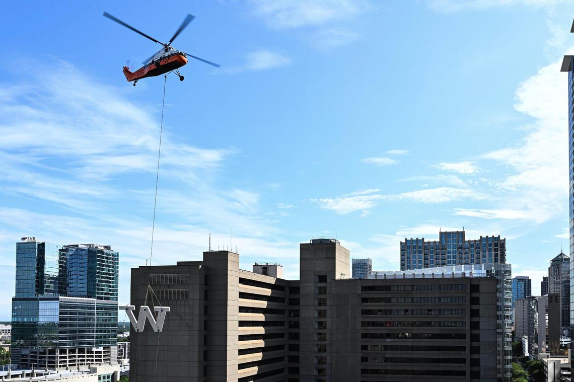 A helicopter hoists the ‘W’ to be placed on the top of the Wells Fargo building in uptown, Sunday, June 15, 2025, in Charlotte, N.C.