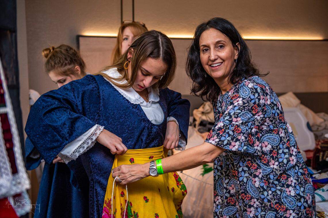 Elaine Mahairas dresses a dancer in preparation for the 2020 Hellenic Dance Festival in Orlando. Mahairas runs the costume room at Holy Trinity Greek Orthodox Cathedral in Charlotte. Each costume she makes is true to the region where the dance originated. This dancer’s costume represents the village of Lefkopigi in Macedonia.