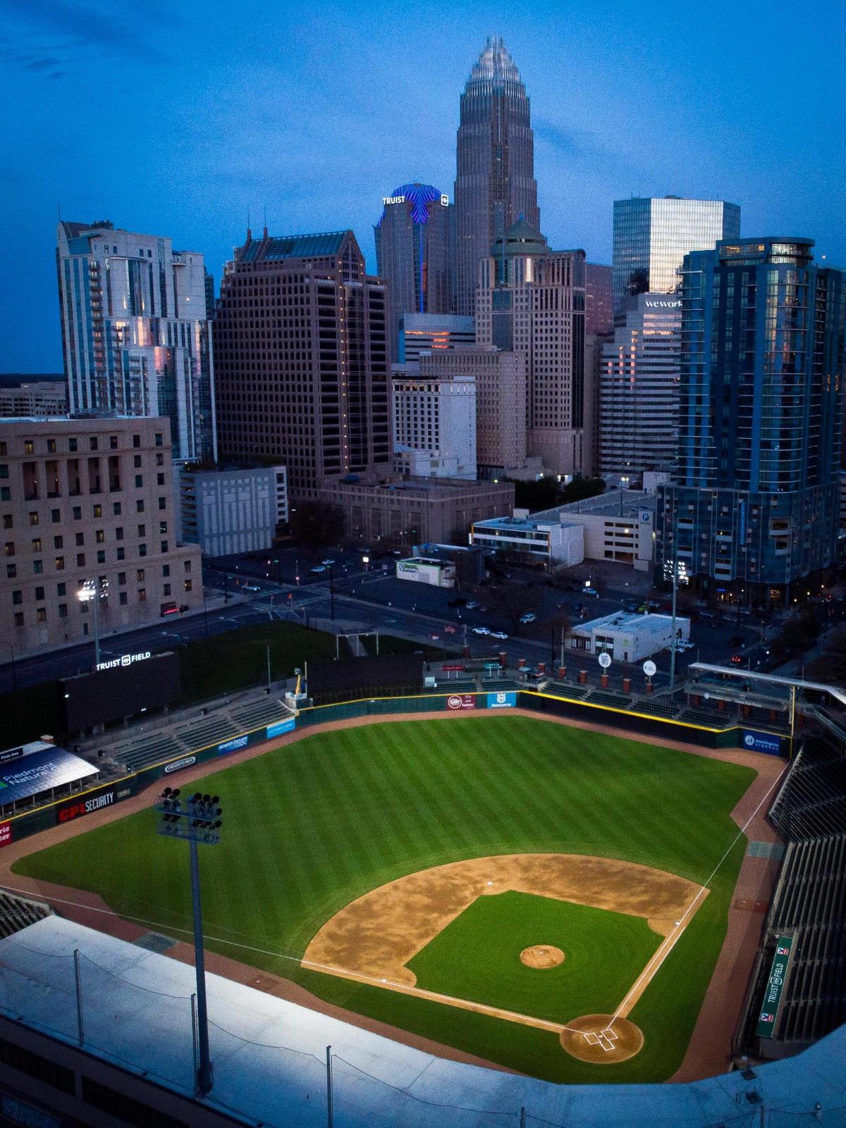 Trust Field, home to the Charlotte Knights sits illuminated against the city skyline in Charlotte, N.C., Monday, March 28, 2022.