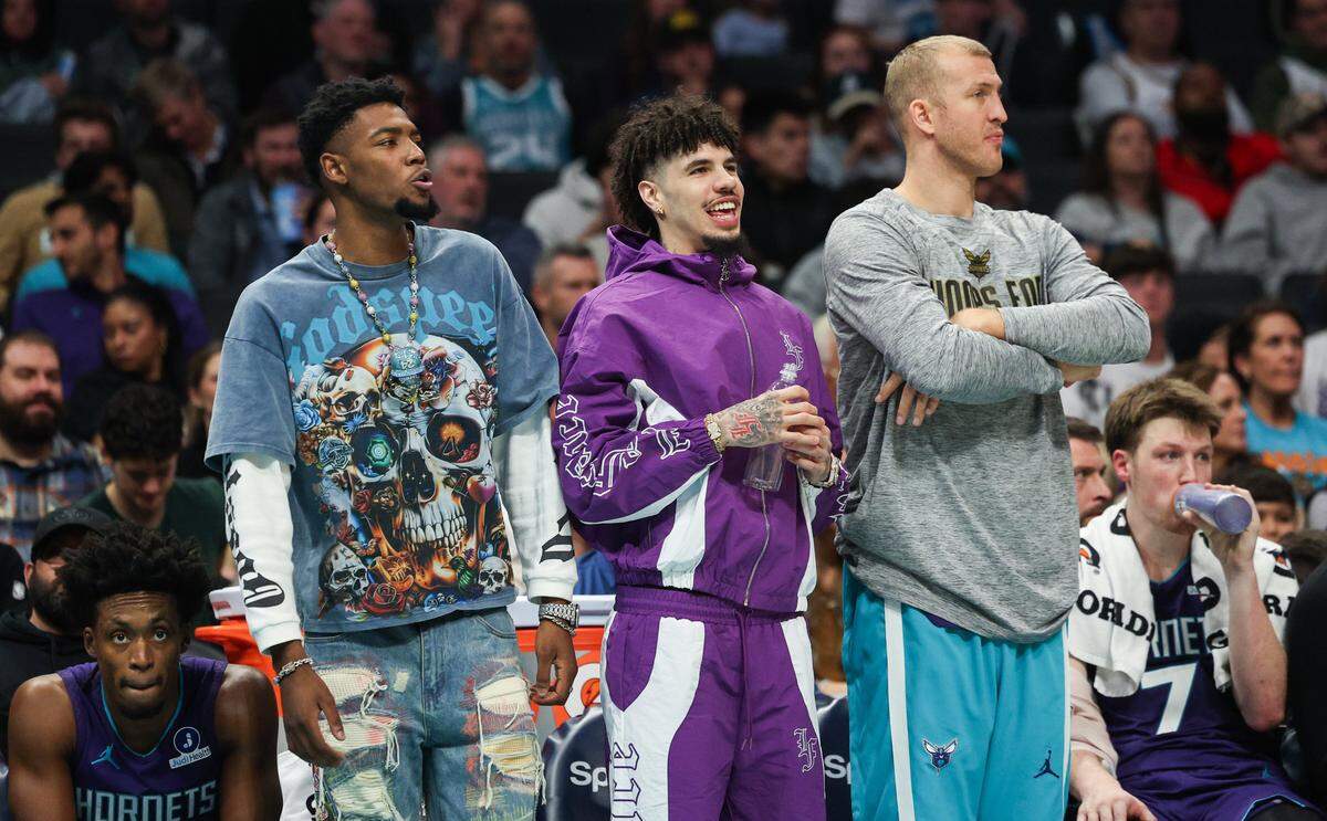 Injured Hornets players Brandon Miller, left, and LaMelo Ball, center, stand with Mason Plumlee on the sideline during the game against the Bucks at Spectrum Center in Charlotte, NC on Wednesday, November 12, 2025.