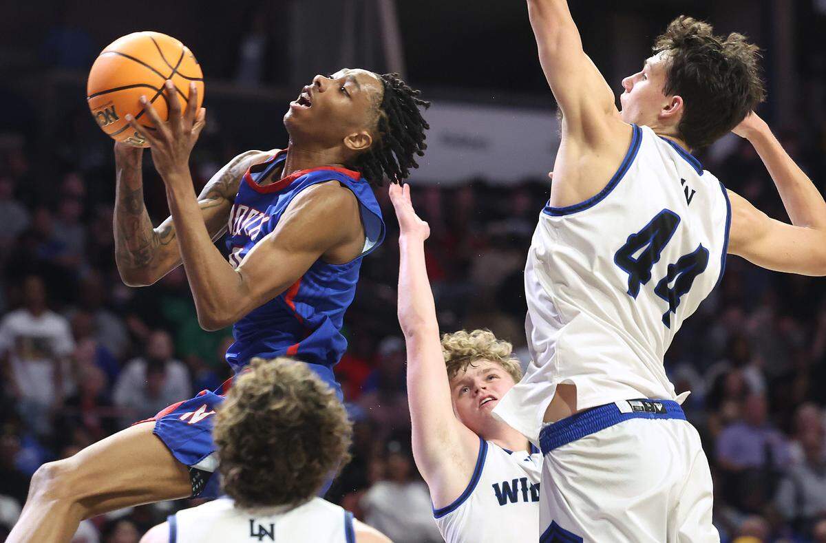 North Meck’s Isaiah Evans, left, drives to the basket past the Lake Norman defense and 6-foot-10 power forward Trent Steinour (44) during fourth-quarter action in the NCHSAA 5A Regional Championship on Thursday, March 14, 2024 at Lawrence Joel Veterans Memorial Coliseum in Winston-Salem, NC. North Meck defeated Lake Norman 65-61 in overtime to move into Saturday’s final against New Hanover.