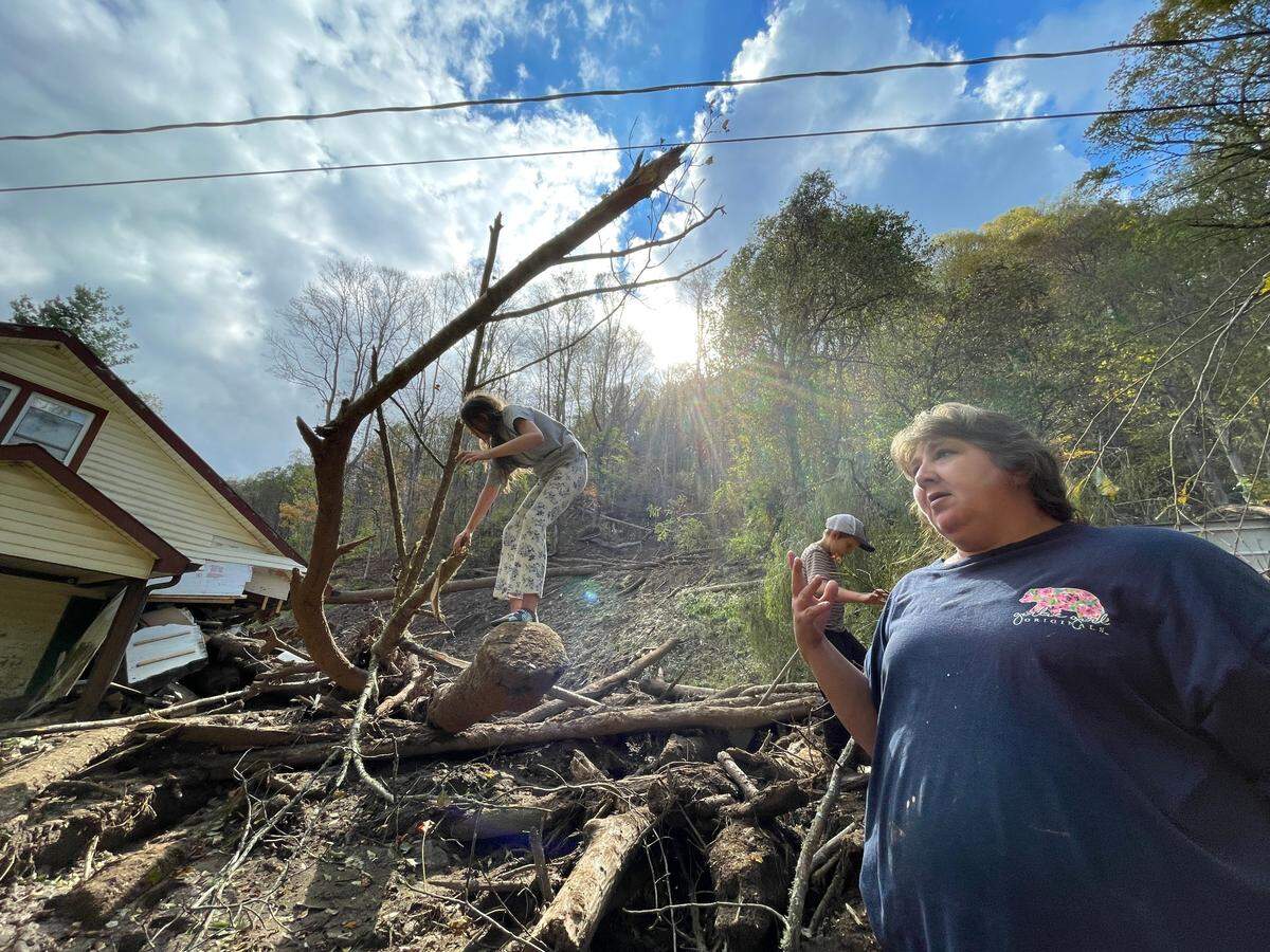 Ashley Clawson and her children navigate thick mud as Logan Brown, 17, digs out his family’s dirt bikes from a sludged shed on Thursday, Oct. 3, 2024. Hurricane Helene buried many items.