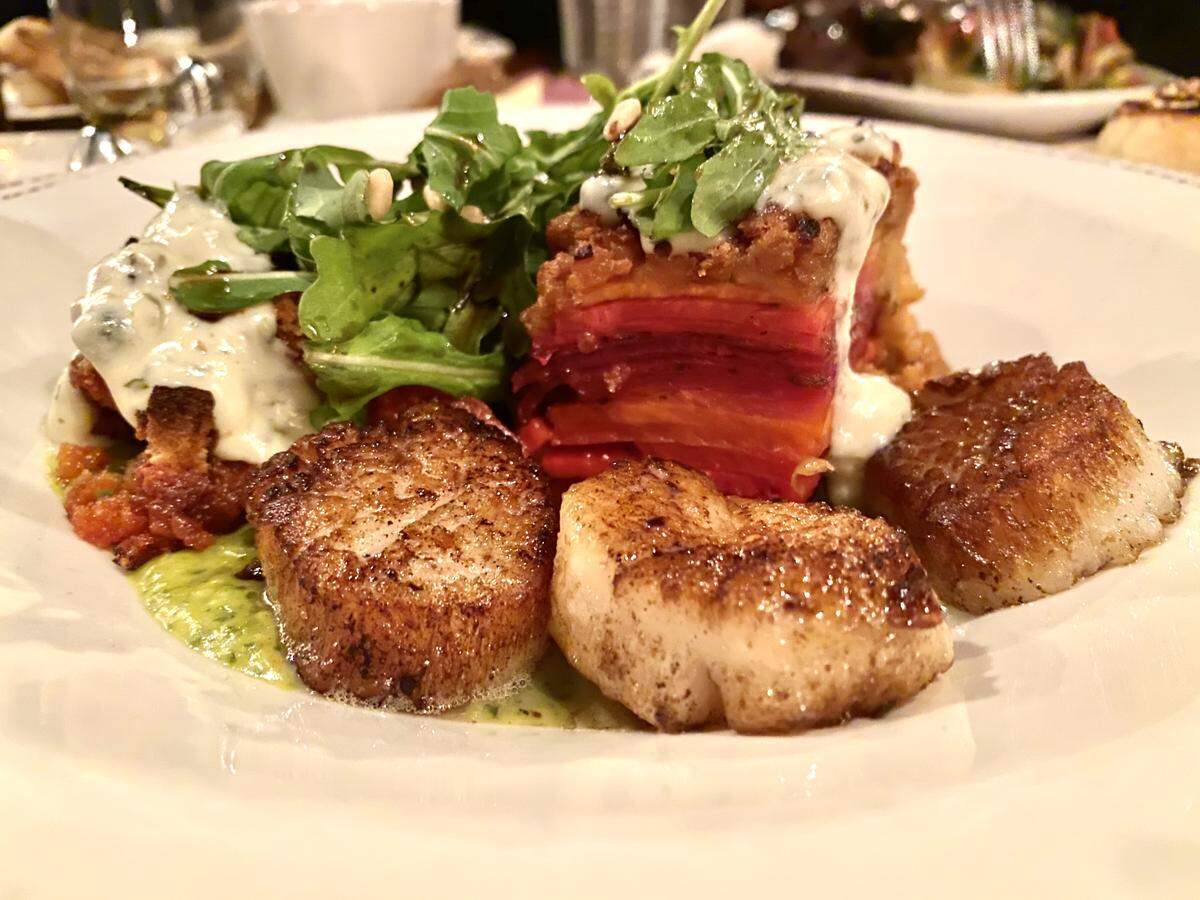 Crepe Cellar’s Seared Scallops with fall spices, rooster root vegetable gratin, green peppercorns caper cream sauce, topped with arugula, pine nut, pomegranate salad.