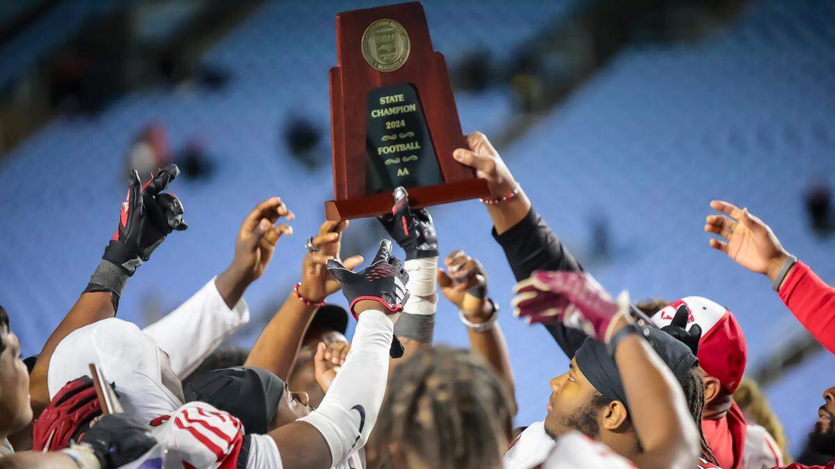The Monroe Redhawks hold up their State Championship plaque after beating Northeastern at the NCHSAA 2A final at Kenan Stadium in Chapel Hill on Dec 21, 2024