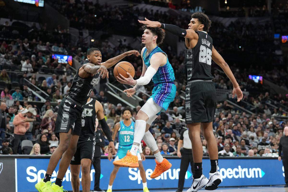  Charlotte Hornets guard LaMelo Ball (1) scoops the ball around San Antonio Spurs guard Blake Wesley (14) and forward Dominick Barlow (26) in the first half at Frost Bank Center.