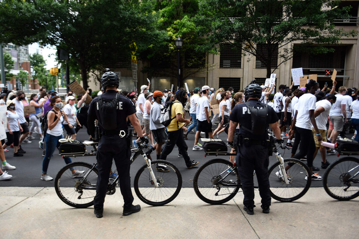 Police line the sidewalks of Uptown as what organizers estimate to be a mile-long procession of demonstrators pass by during an It Ends Now Charlotte rally on May 31, 2020.