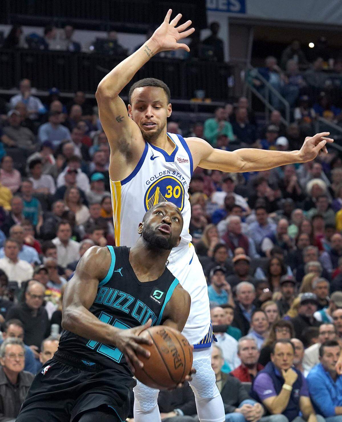 Charlotte Hornets guard Kemba Walker, front, drives to the basket around Golden State Warrior guard Stephen Curry Monday. Walker scored 23 points in the Hornets’ 11 point loss, shooting 9-for-24.