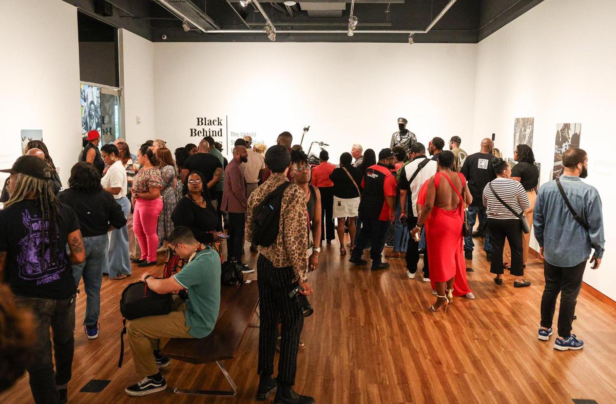 Attendees admire the photos in “Black Behind Bars” exhibit by photographer Alvin C. Jacobs, at the Harvey B. Gantt Center for African-American Arts + Culture in uptown Charlotte. Jacobs said his goal was to capture “the spirit, not just the style” of the Black motorcycle culture.