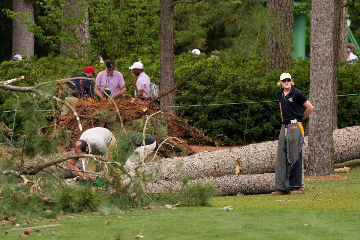 Volunteers and staff secure the area around where a tree fell near the 17th tee during the second round of The Masters golf tournament. 
