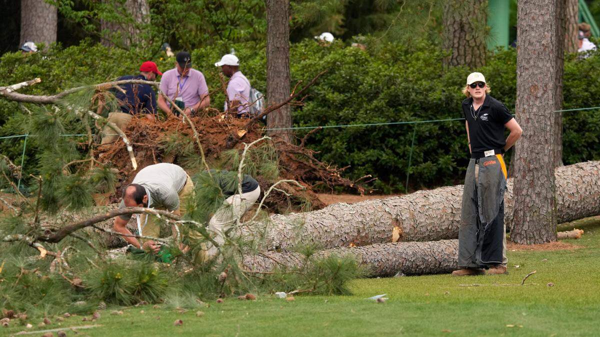 Volunteers and staff secure the area around where a tree fell near the 17th tee during the second round of The Masters golf tournament.