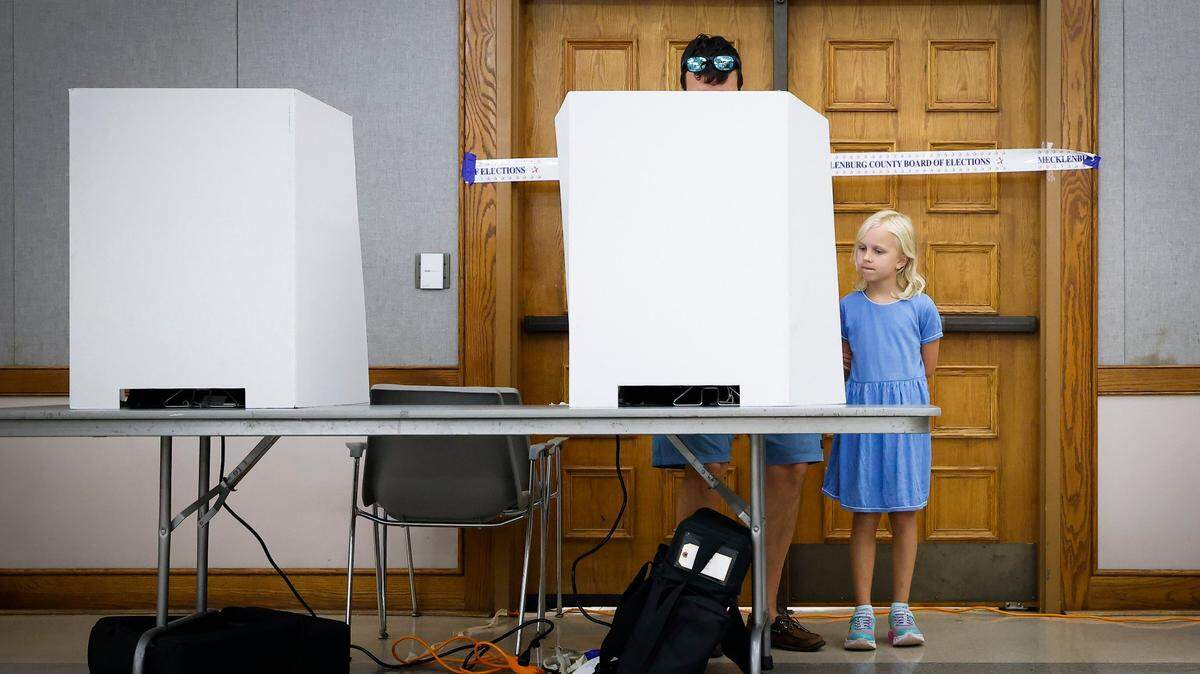 Penelope Hassey, 7, looks on as her father Matthew Hassey votes in Tuesdays election at St. Johns Baptist Church in Charlotte.