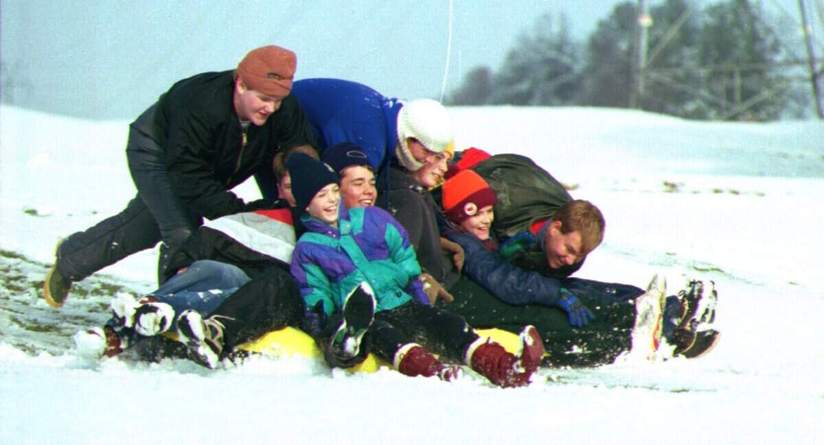Everybody's a kid when it snows, and the more the merrier as about 10 boys share a sled at Lakewood Golf Links in Cramerton on December 24, 1993. The youths, aged 9 to 18, were getting the most from the rare snowfall, which mostly melted by midday.