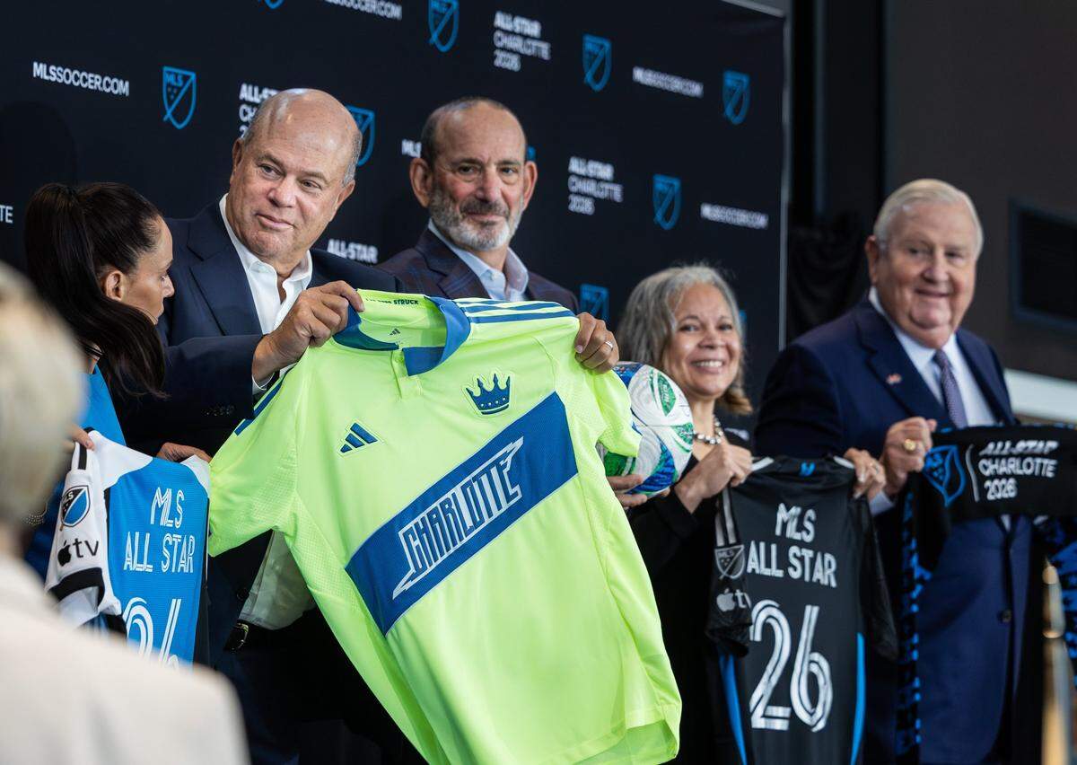 David Tepper, left, holds up a new jersey inspired by Charlotte’s first professional soccer team, the Carolina Lightnin’, during a press conference announcing the 2026 MLS All-Star Game will be held at the Bank of America Stadium in Charlotte Wednesday, July 16, 2025.