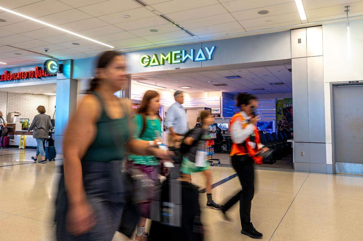 Travelors walk past the Gameway lounge in Concourse E at the Charlotte Douglas Airport, Wednesday June 18, 2025. The lounge offers passes for different time limits, including unlimited, to accommodate their patrons’ differing layover times.