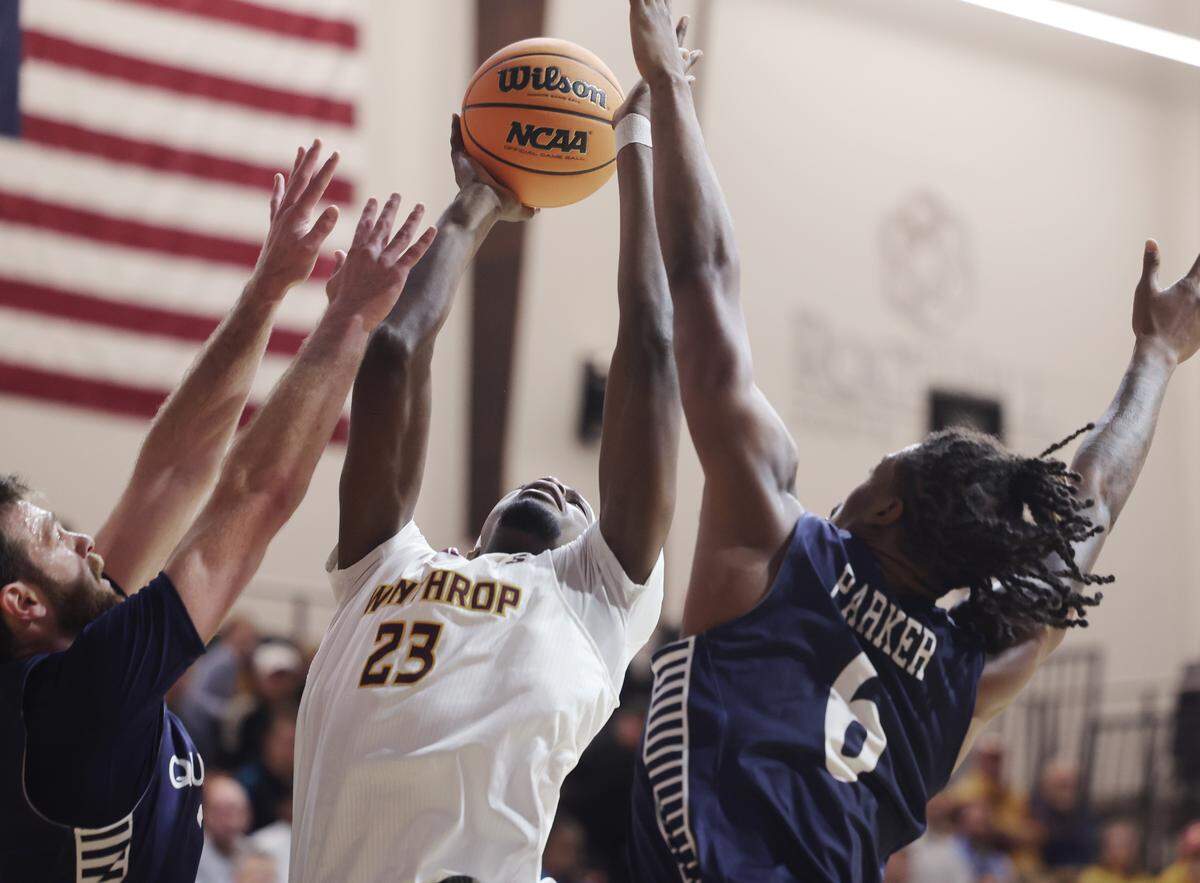 Winthrop University's Ed Nnamoko takes the shot as Queens University's Yoav Berman, left, and Avantae Parker defend on Monday in Rock Hill on the opening day of the college basketball season.