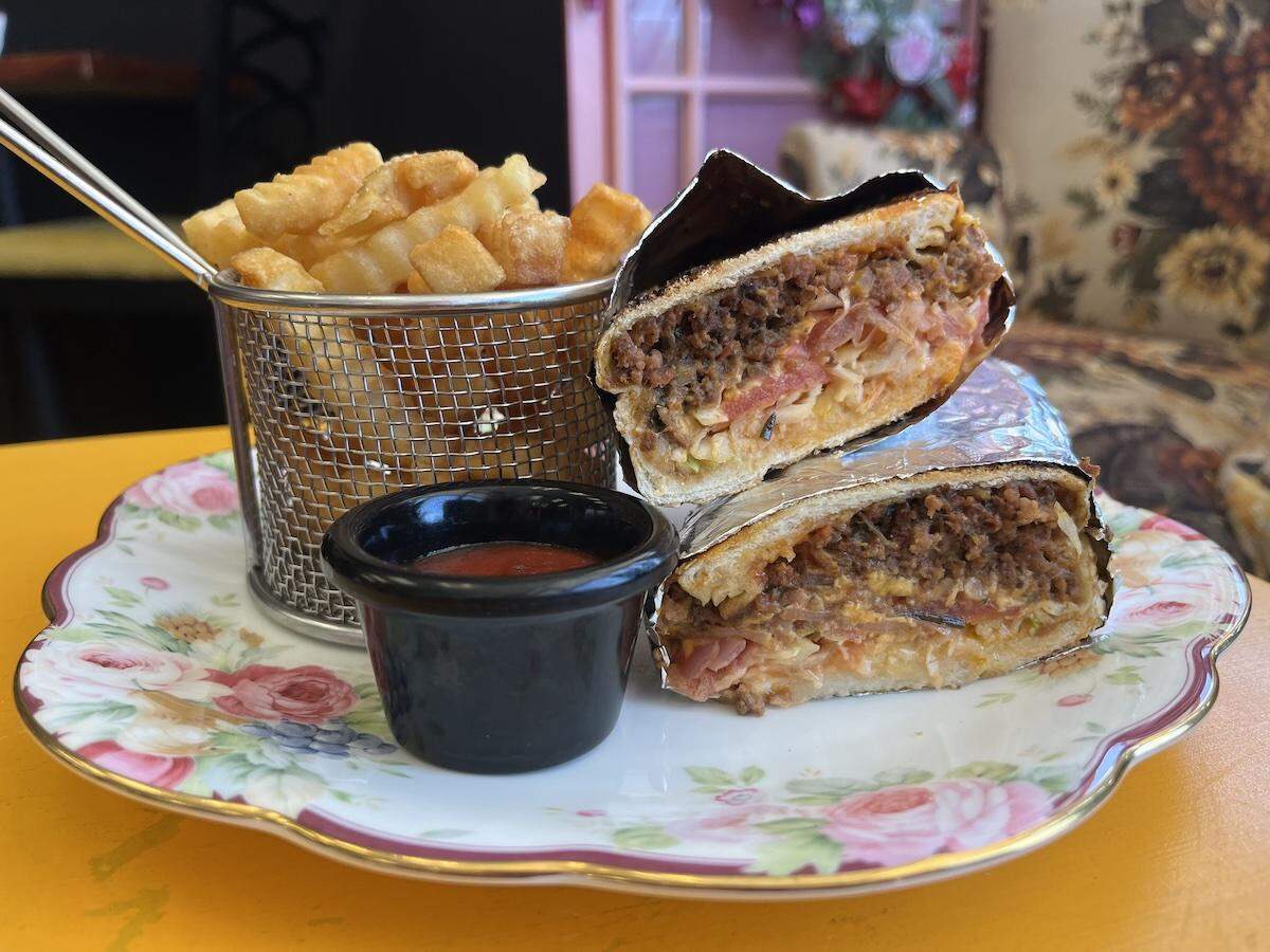 La Dolcekca owner Karina Cooper’s daughter, Sharon Chanelle, adds pico de gallo to the classic chop cheese sandwich, which sells for $18 with a side of fries.