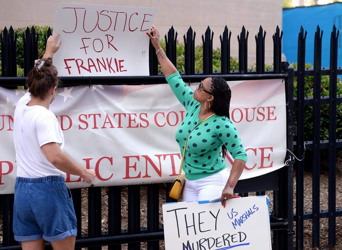 Community organizer Jamie Marsicano, left and Tanua Wallace, right, attempt to hang a sign on fencing at the United States Courthouse at 401 W. Trade Street in Charlotte, NC on Tuesday, July 6, 2021. Protesters held a vigil in memory of Frankie Jennings who was shot and killed by a federal marshal on Tuesday, March 23, 2021. Wallace is a sister of Frankie Jennings.