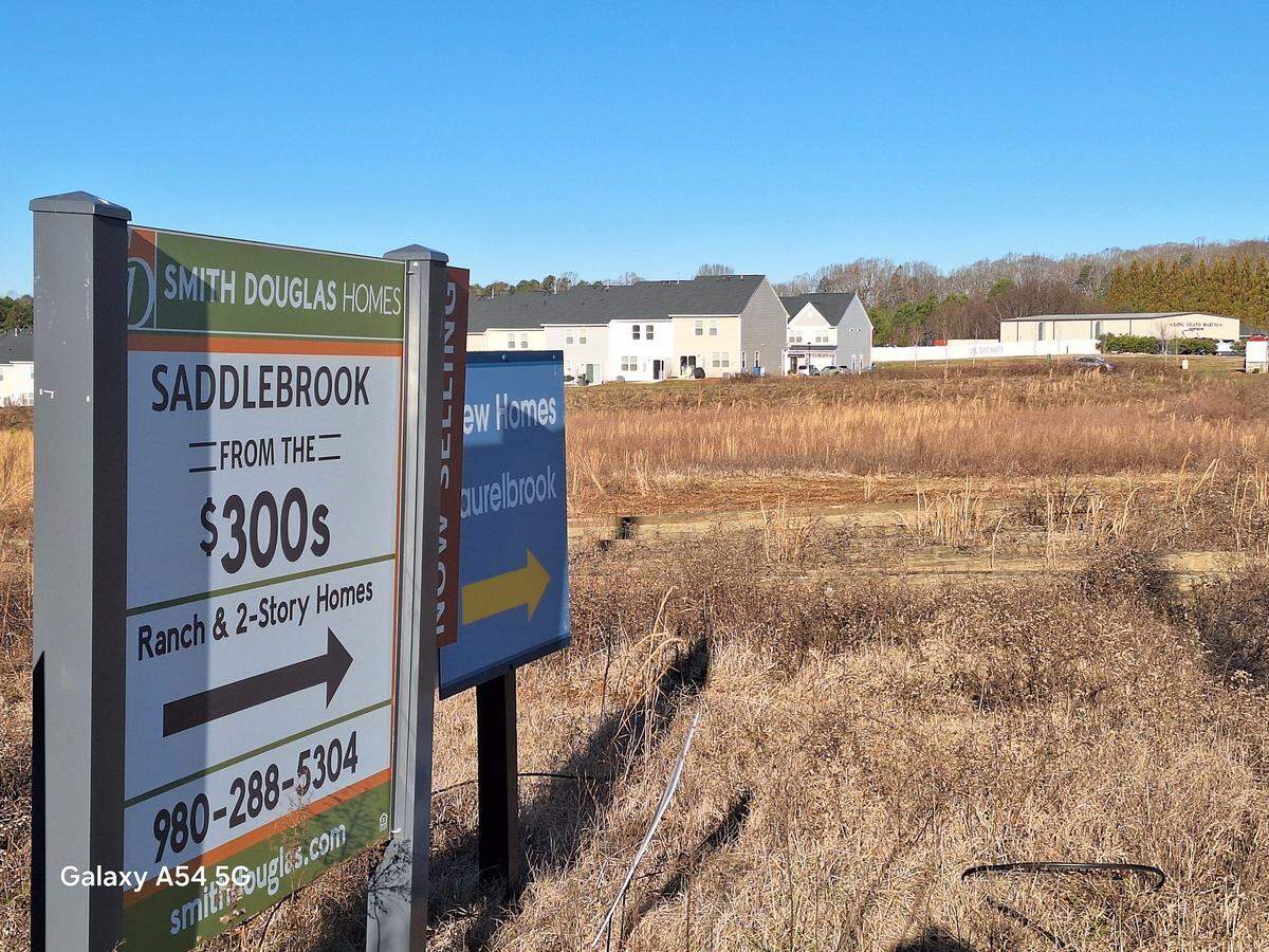 Signs for new homes point down Sherrills Ford Road in Terrell NC. Shown in the distance is the weed-filled acreage where Terrell Town Center Area 2 is planned.