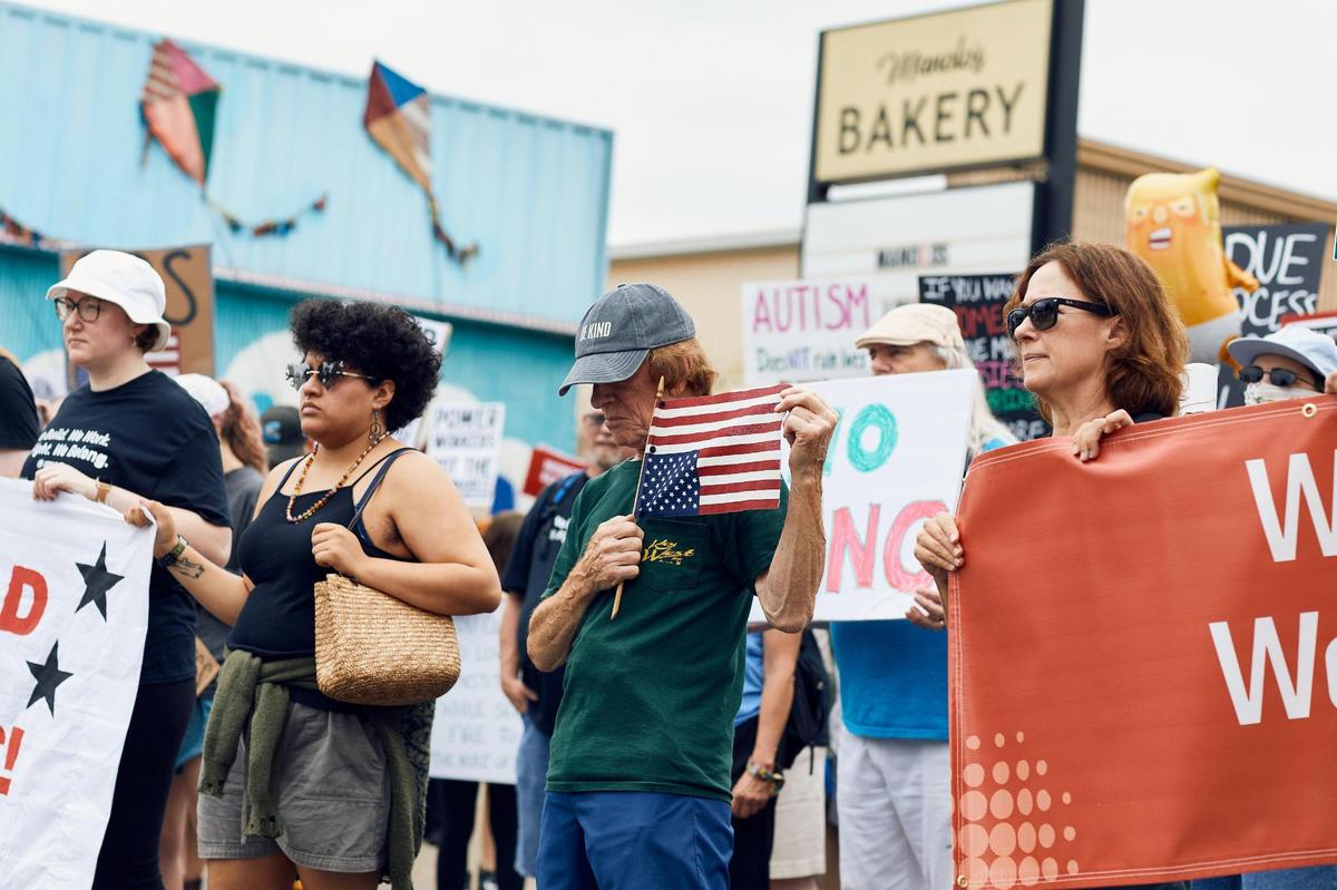 A man holds his American flag upside down in a sign of distress for the country. A crowd of over 1000 people showed up to march on Central Avenue for the May Day Trump Protests in Charlotte, North Carolina on May 3, 2025.