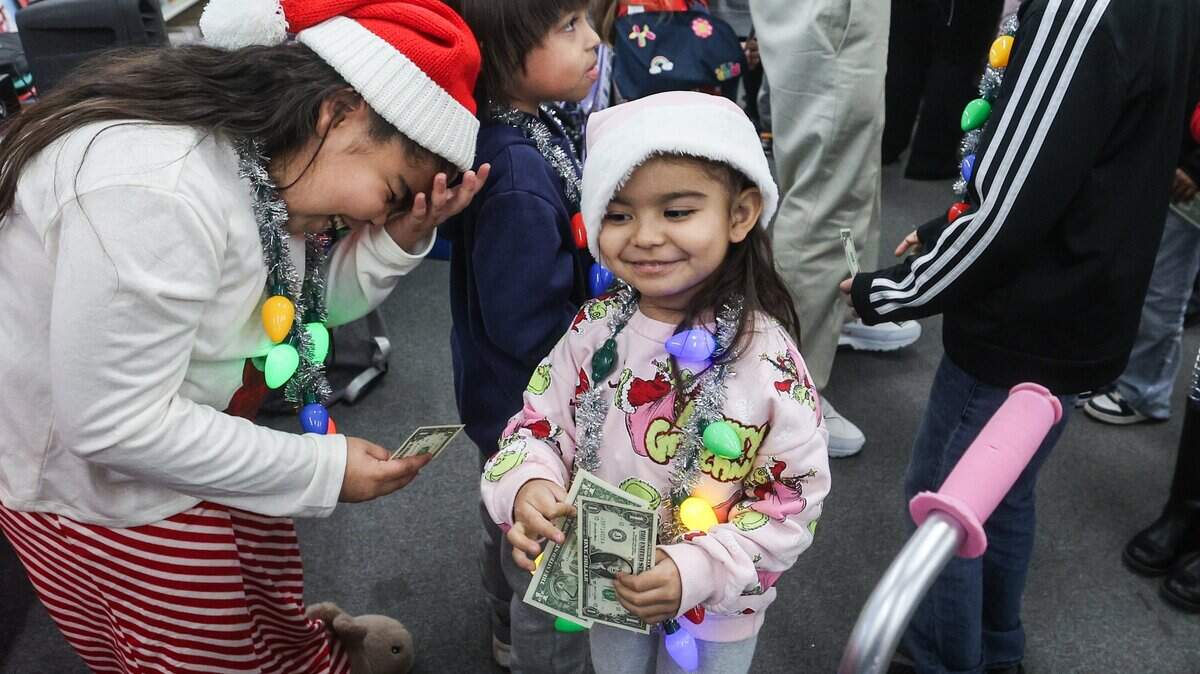 Fernanda Molina, 8, left, laughs as her sister Esther, 3, picks up an extra dollar during a secret Santa gift giveaway at the Mighty Dollar store in Gastonia on Dec. 12.