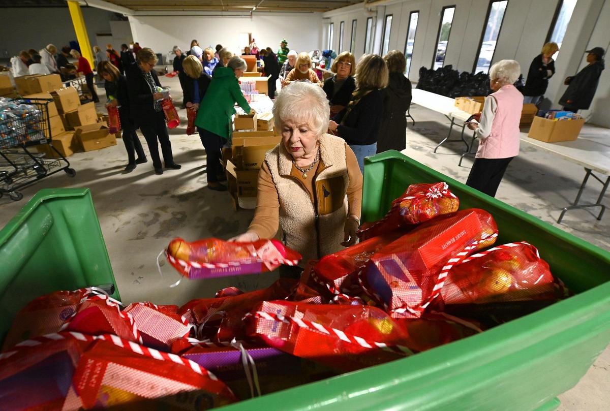 Marlene Captain, a volunteer with the Salvation Army Women’s Auxiliary of Greater Charlotte, places a stocking into a container on Tuesday, November 15, 2022. The Salvation Army will provide thousands of children with Christmas holiday gifts.