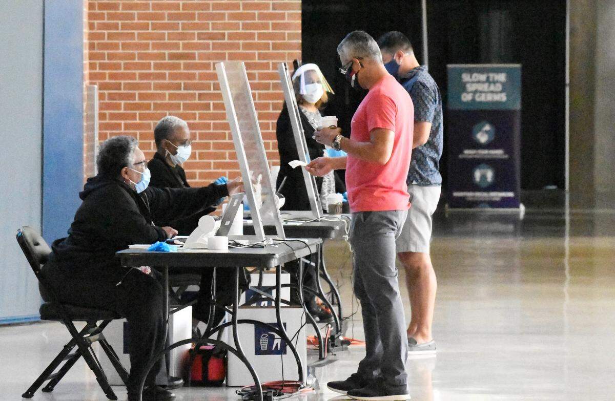 Voters check-in at the Spectrum Center early-voting site on Thursday, October 15, 2020.