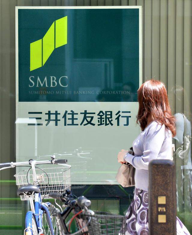 A woman walks in front of a signboard of Japan's Sumitomo Mitsui Banking Corp (SMBC) in Tokyo on May 15, 2013. Sumitomo Mitsui Financial Group Inc. reported its annual net income jumped more than 53 percent in the year to March to 794.06 billion yen (7,42 billion euros). AFP PHOTO / KAZUHIRO NOGI        (Photo credit should read KAZUHIRO NOGI/AFP via Getty Images)