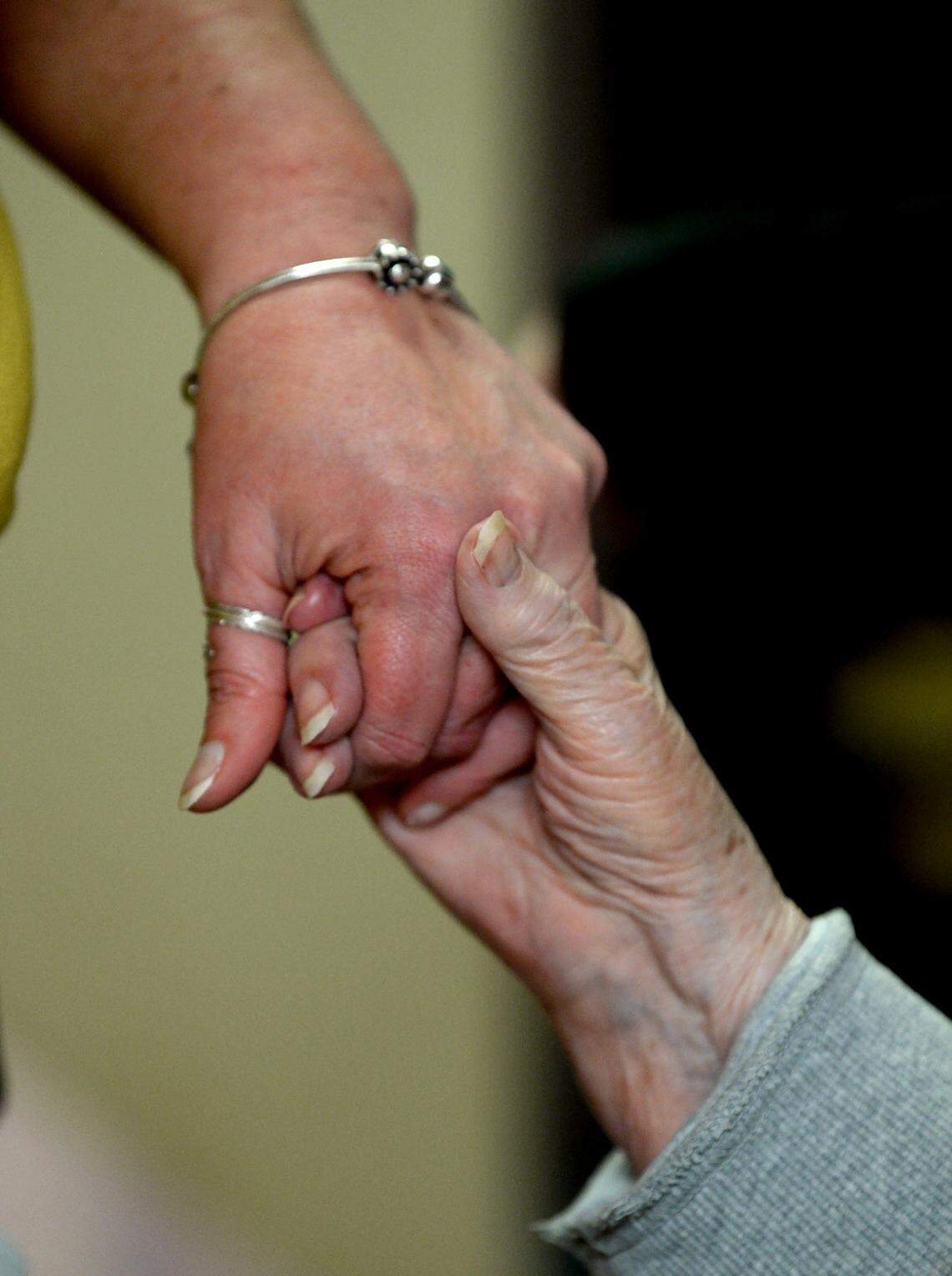 A caregiver at a nursing home in Salisbury holds hands with a resident.