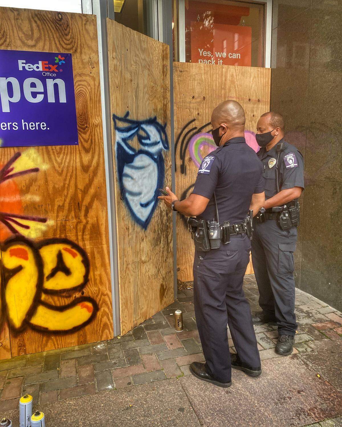Two Charlotte-Mecklenburg police officers participate in a Charlotte Art League project. A property management company asked CAL to paint over boarded up windows at one of its properties. CAL turned it into a community project and asked CMPD officers to help.