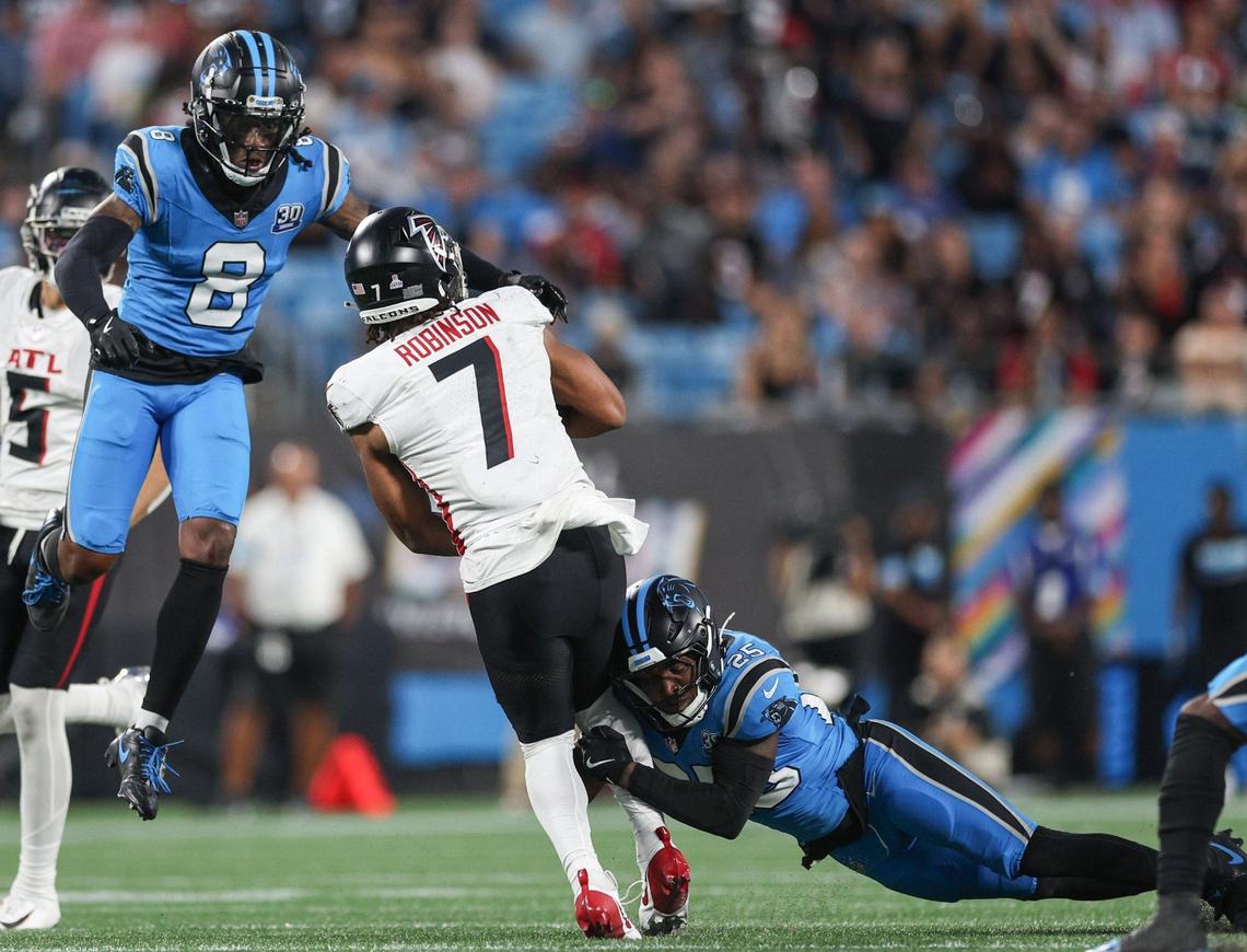 Panthers defensive backs Jaycee Horne, left, and Xavier Woods, right, swarm Falcons runningback Bijan Robinson during the game at Bank of America Stadium in Charlotte, NC on Sunday, Oct. 13, 2024.