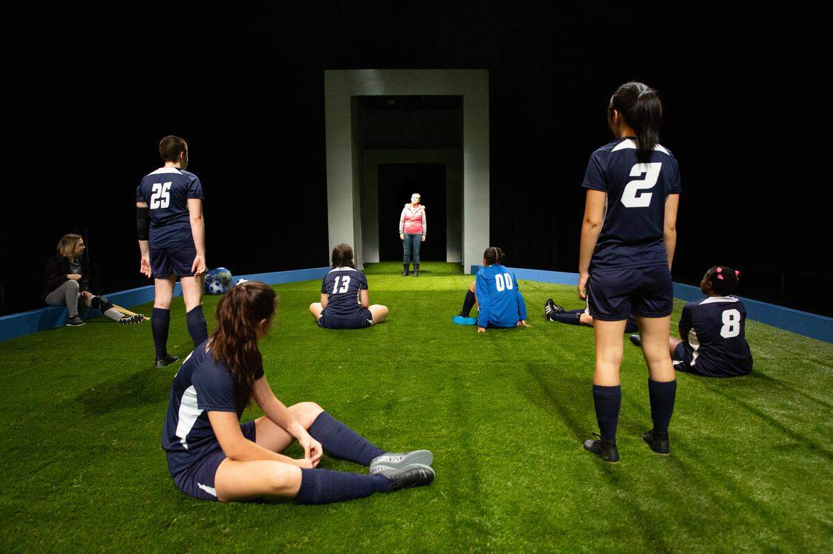 “The Wolves” features a turf-covered set designed and lit by Evan Kinsley that runs the length of Queens University’s Hadley Theater.