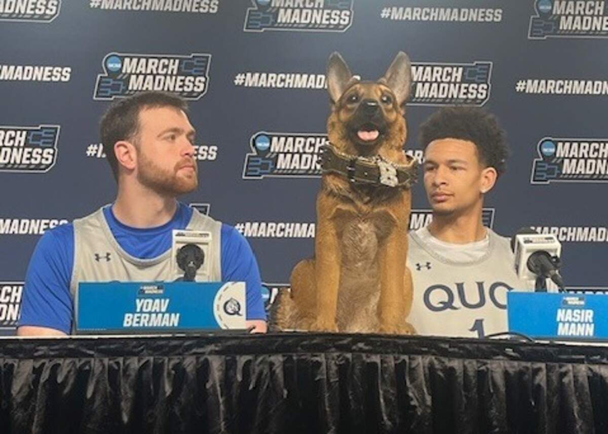 Queens players Yoav Berman and Nasir Mann sit with Buddy, the team’s “mascot,” at the Royals’ NCAA Tournament press conference on Thursday in St. Louis.