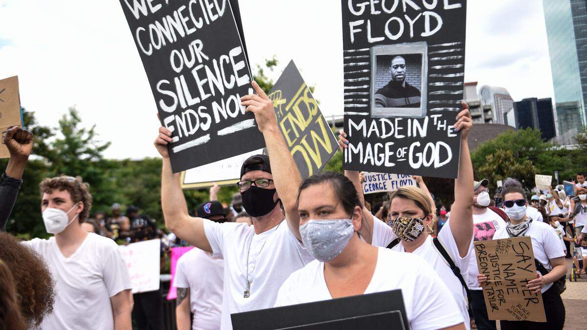 Demonstrators carry signs as they return to First Ward Park following a march organized by It Ends Now Charlotte on May 31, 2020.