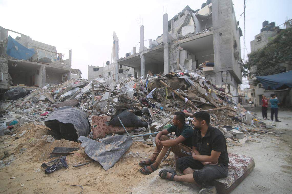 Palestinians sit by the rubble Abu Helal family in Rafah refugee camp, Gaza Strip, Monday, Oct. 9, 2023. The strike killed dozens of people.(AP Photo/Hatem Ali)