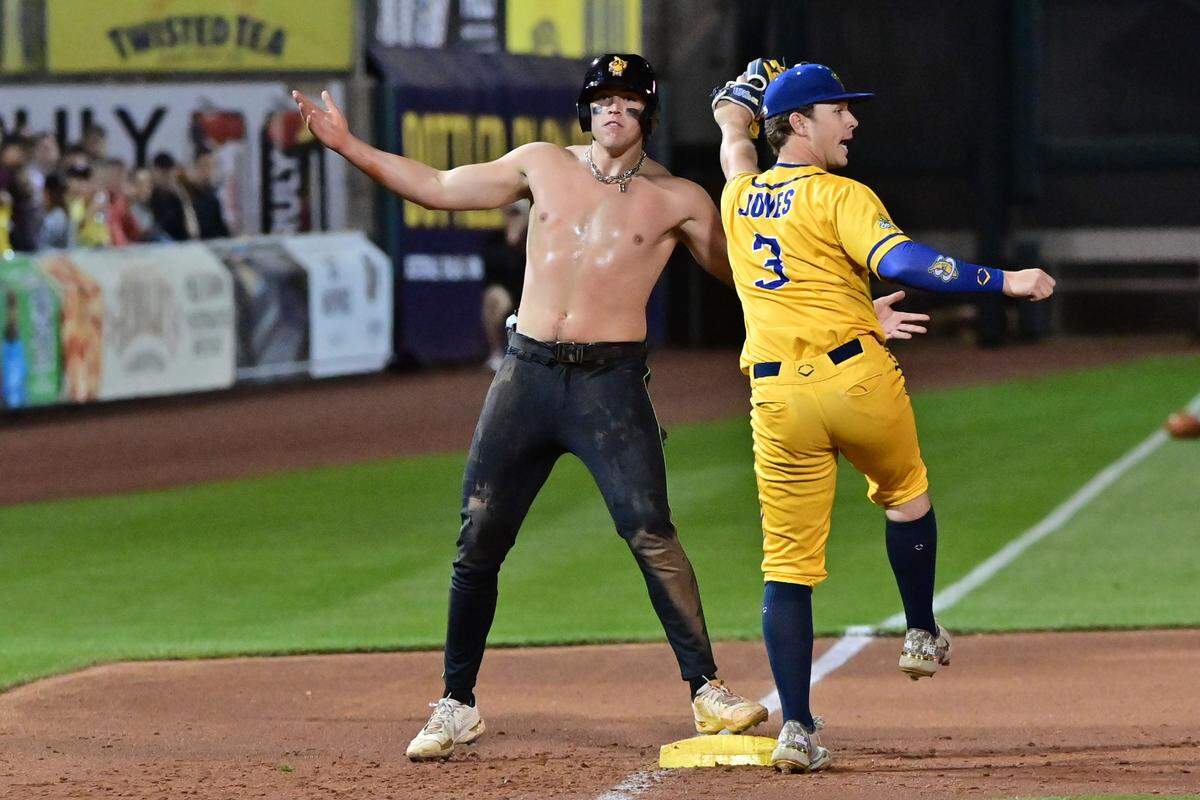 Savannah Party Animals third baseman Bryson Bloomer (8) triples as Savannah Bananas third baseman Eric Jones Jr (3) reacts during a game in Scottsdale, Arizona.