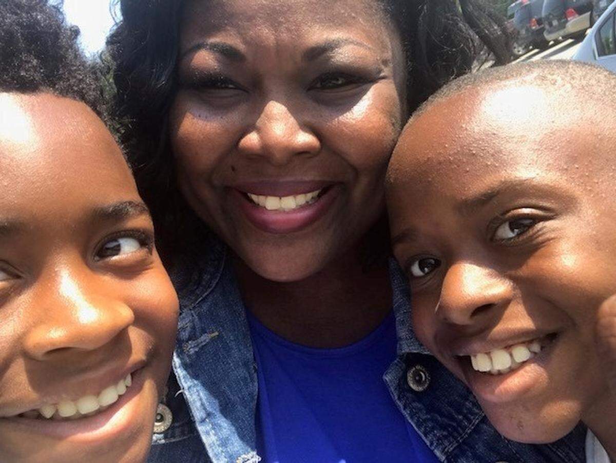 Joy Graham (center) smiles alongside her nephews, Jahkai and Kinrick, who have become her sons.