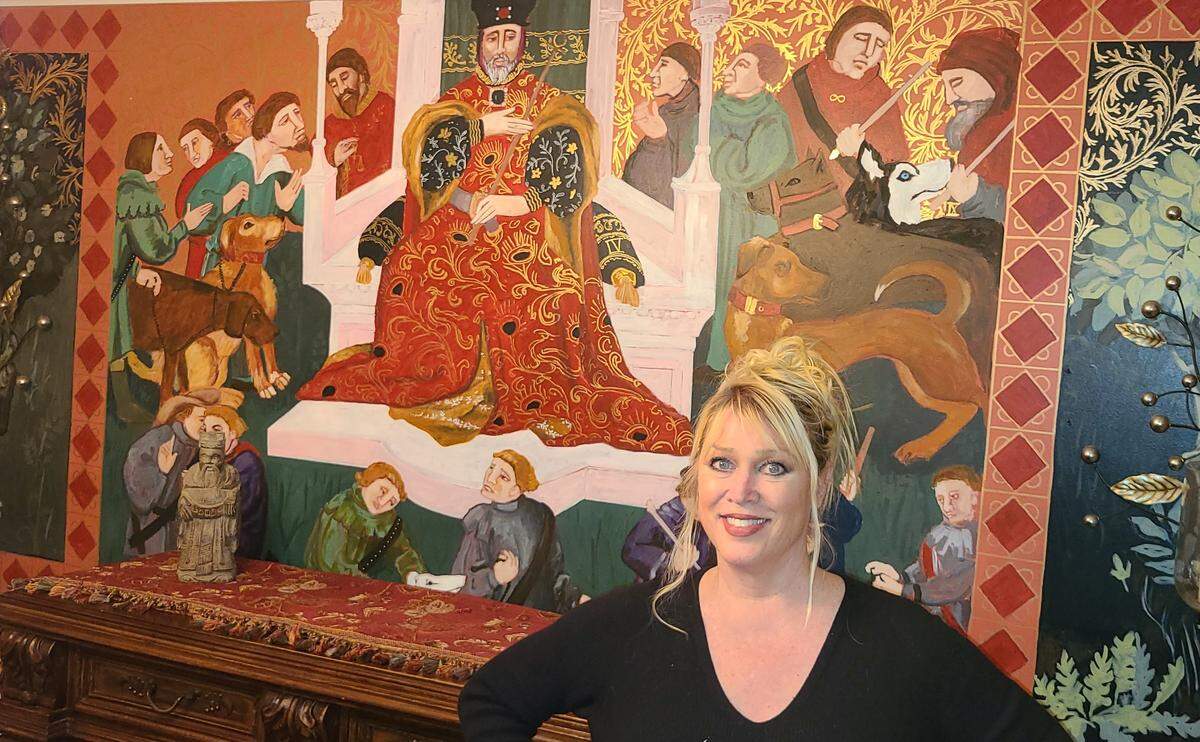Charlotte artist Emily Andress in front of the elaborate mural she painted on her dining room walls. She says it was her way of coping with the COVID-19 pandemic and strengthen her connection to her grandmother. 