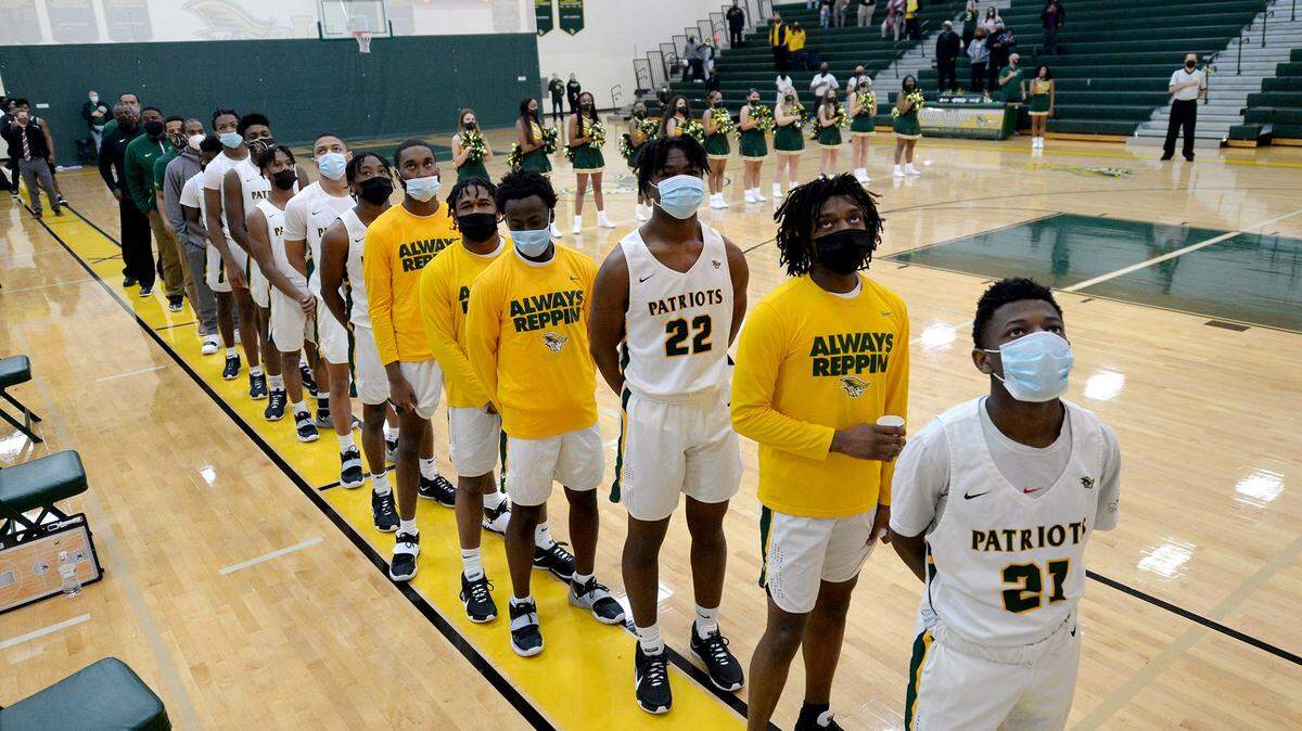 The Independence Patriots stand for the National Anthem wearing face masks due to the COVID-19 virus on Tuesday, February 9, 2021. The Patriots hosted their rival Butler Bulldogs in a basketball game. The rival game was the first for the schools since CMS Supt. Earnest Winston shut teams down last month. All fans were asked a series of questions concerning and temperature checked before being allowed into the gym.