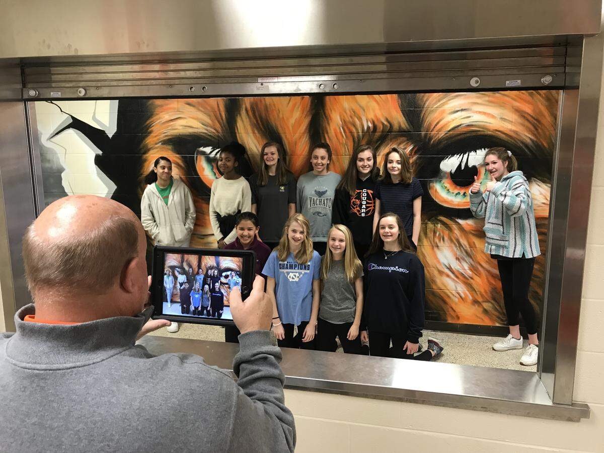 Carmel Middle School Athletic Director Brian Poore snaps a photo of the girls basketball team on the morning Shane Pierce’s mural was unveiled in the school’s hallway.