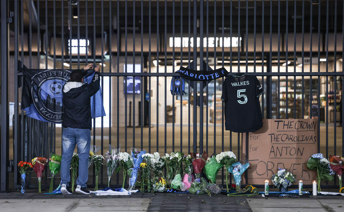 A mourner hangs up a flag during a vigil for Charlotte FC defender Anton Walkes Charlotte, N.C., on Thursday, January 19, 2023.