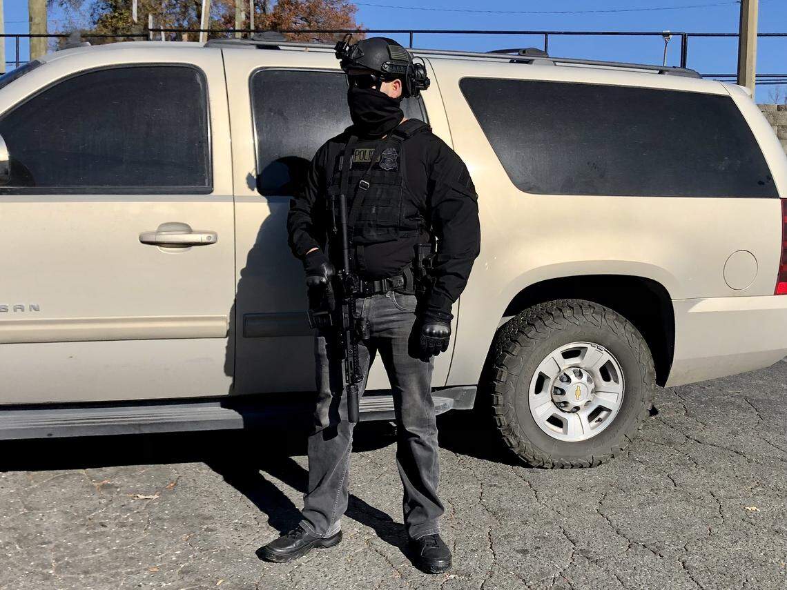 A U.S. Customs and Border Patrol agent stands guard near one of the team’s vehicles at the Compare Foods on North Tryon St. in Charlotte, NC on Monday, November 17, 2025. 