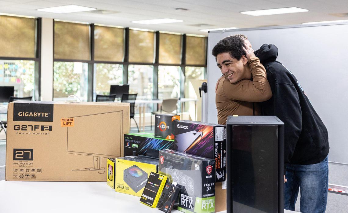Kaliek Wade, right, is hugged by his mother, Kimberly Whorley, after receiving the components to build a PC at Stiegler Edtech in Charlotte, N.C., on Wednesday, November 23, 2022.